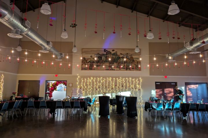 Decorated banquet hall with string lights, tables, chairs, and a mural on the wall.