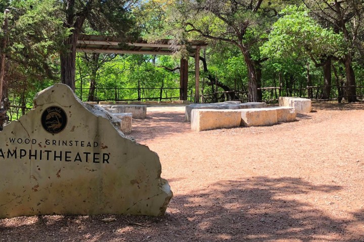 a sign on a dirt ground with trees in the background