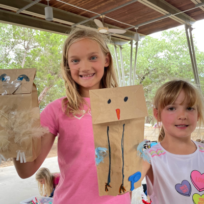 Two kids holding paper bag puppets at Blue Hole Nature Camp.