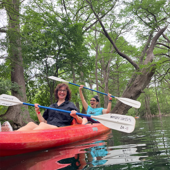 a person riding on the back of a boat next to a tree
