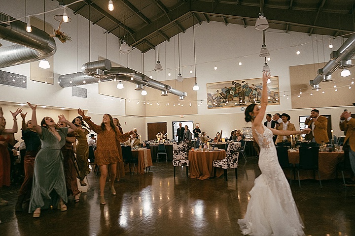 Candyce + Hayden | Wedding in Wimberley Texas Bride tosses bouquet to women at indoor wedding reception.