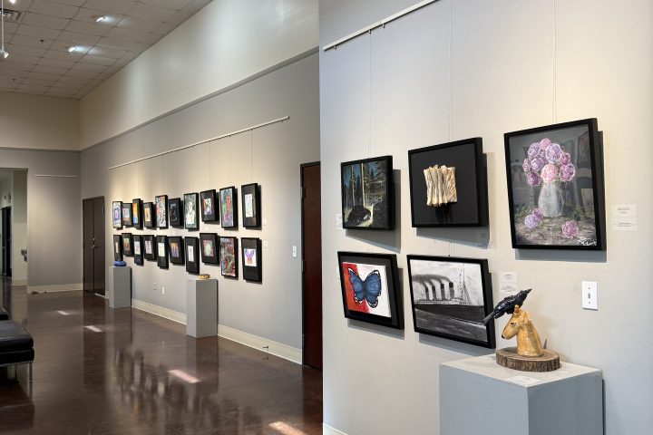 Gallery interior with framed artworks on walls and sculpture on pedestal.