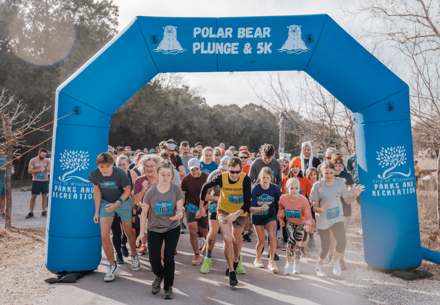 A group of runners starting a race under a blue inflatable arch labeled 'Polar Bear Plunge & 5K'.