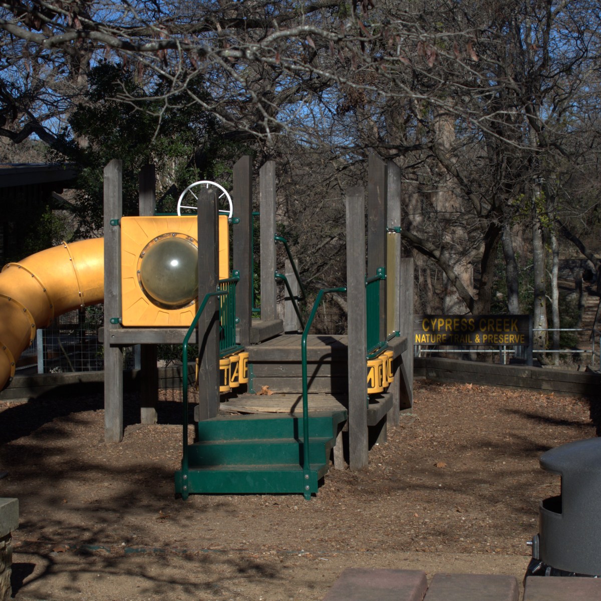 Playground with slide and climbing structure under trees.