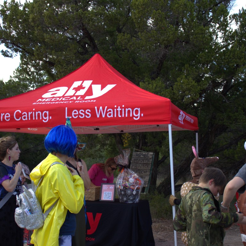 People in costumes gather under a red medical tent.