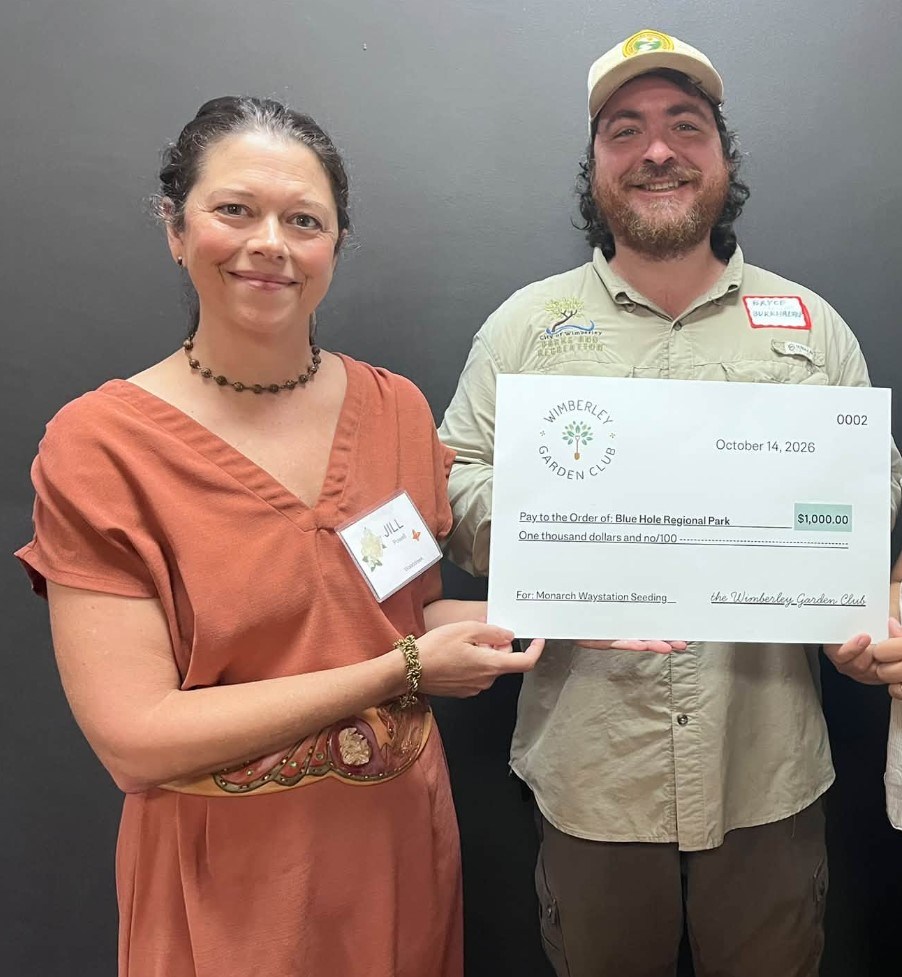 Two people holding a large check for charity donation.